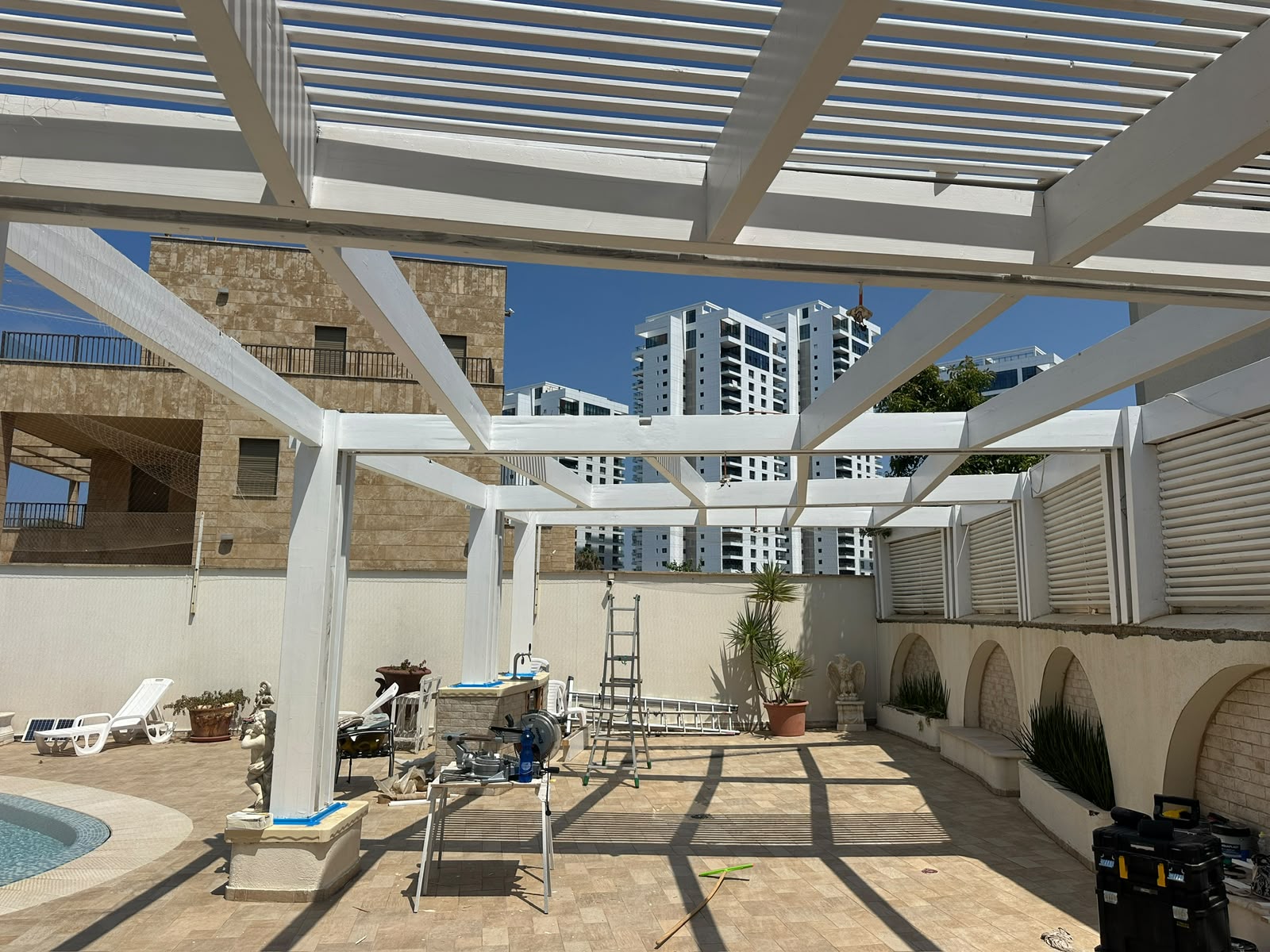 בניית פרגולה לבנה בתהליך עבודה בחצר